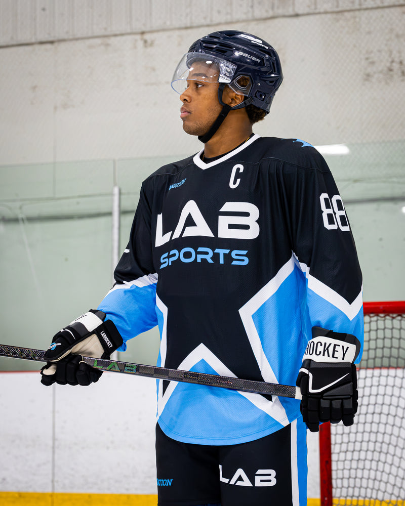 Joueur de la LHJMQ tenant un bâton Pro All Black V2 de LabSports dans un aréna